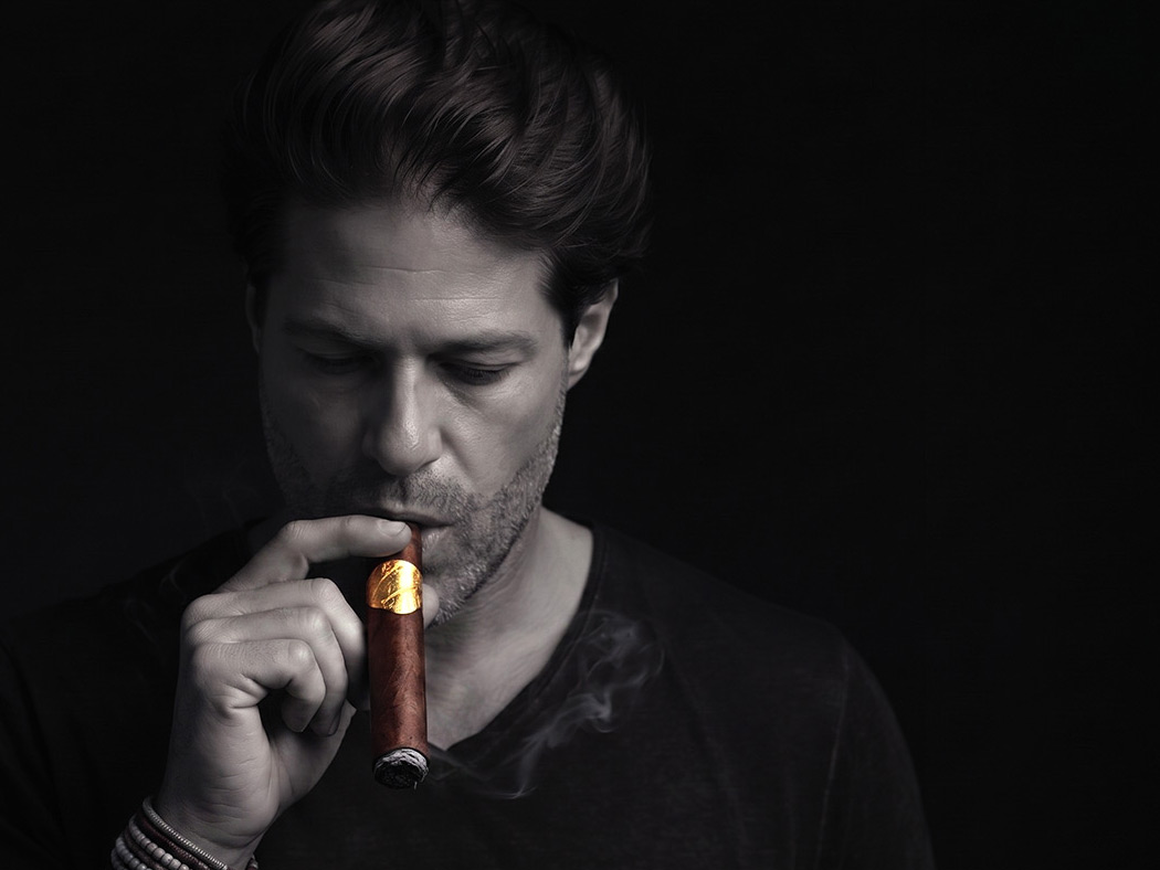 Portrait of founder Stephane Zermatten lighting a Mariposa cigar.